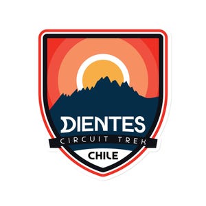 May include: A sticker featuring a shield design with a navy blue mountain range silhouette, an orange and yellow rising sun, and the text "DIENTES CIRCUIT TREK CHILE". The sticker has a red and black border.