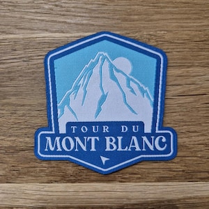 May include: Blue and white embroidered patch with a mountain and the text "Tour du Mont Blanc".