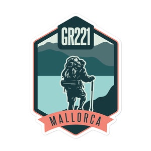 Op de afbeelding: Een groene en blauwe geïllustreerde sticker met een wandelaar die een rugzak en een wandelstok draagt. De sticker heeft de tekst "GR221" en "MALLORCA" in wit.