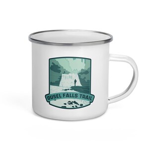 May include: White enamel camping mug with a green and blue illustration of a waterfall and a person standing on a rock. The text "Ousel Falls Trail" is printed below the illustration.