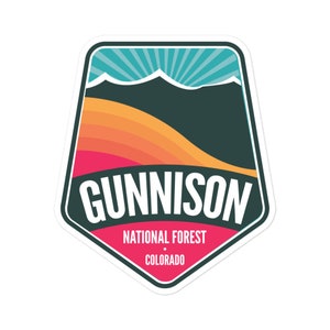 May include: A sticker with a retro design featuring a mountain range, a sunrise, and the text "GUNNISON NATIONAL FOREST COLORADO".