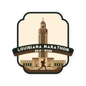 May include: A sticker featuring a stylized illustration of the Louisiana State Capitol building in Baton Rouge, Louisiana. The sticker is beige with brown accents and features the text "Louisiana Marathon 26.2 - 2026" and a silhouette of a runner.