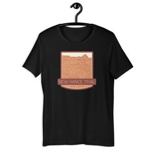May include: Black t-shirt featuring a brown graphic of a canyon landscape and the text "NEW HANCE TRAIL GRAND CANYON".