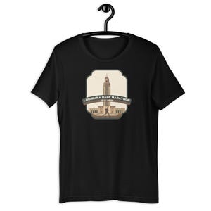 May include: Black t-shirt with a graphic of the Louisiana State Capitol building and the text "Louisiana Half Marathon 12.1.2018".