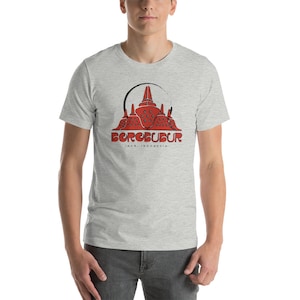 May include: A grey t-shirt featuring a red graphic of the Borobudur temple in Java, Indonesia. The text "BOROBUDUR JAVA, INDONESIA" is printed beneath the image.