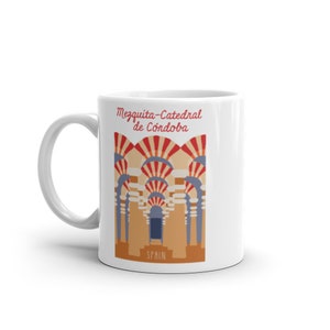 May include: White ceramic mug with a colorful illustration of the Mezquita-Cathedral de Cordoba in Spain. The illustration features red, white, and blue arches with a brown and orange background.