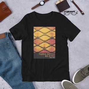 May include: Black t-shirt featuring a geometric design in shades of yellow, orange, and red, with the text "PANNA MEENA KA KUND Jaipur, India" printed below the design. The shirt is made of a soft material.