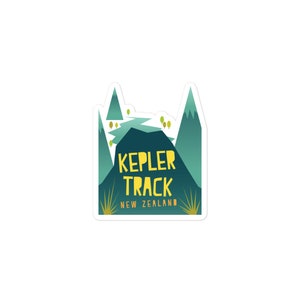 May include: A green and yellow sticker with a stylized illustration of mountains and a river. The text "KEPLER TRACK NEW ZEALAND" is printed on the sticker.