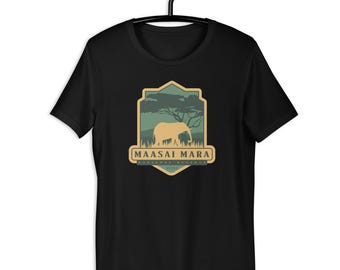 May include: Black t-shirt with a shield-shaped graphic of an elephant and a tree. The text "MAASAI MARA" is below the graphic. The t-shirt is displayed on a black hanger.