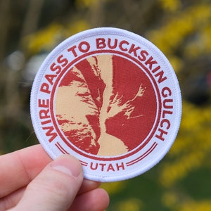 May include: White round patch with red text that reads "Wire Pass to Buckskin Gulch - Utah". The patch features a red and yellow image of a canyon.