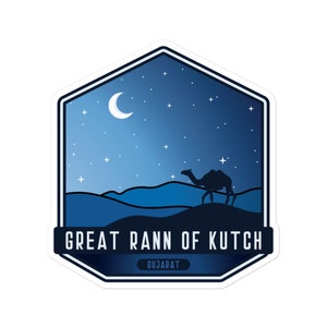 Può includere: Un adesivo con una scena notturna desertica. Mostra la silhouette di un cammello che cammina sotto un cielo stellato e una luna crescente. Il testo "GREAT RANN OF KUTCH" e "GUJARAT" è visualizzato su uno striscione blu scuro.