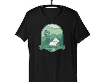 May include: Black t-shirt featuring a green and white graphic of a hiker with a backpack and a dog, with the text "Bartram Trail" in a stylized font. The design is set within a green, shield-shaped frame.