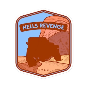 May include: A sticker featuring a red Jeep driving through a red rock canyon with the text "HELLS REVENGE UTAH" in a white outline.