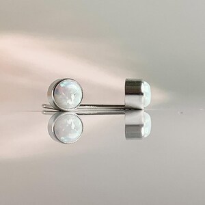May include: A pair of silver stud earrings with white opal stones.