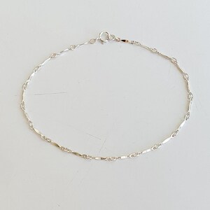 May include: A silver chain anklet with a delicate, linked design.