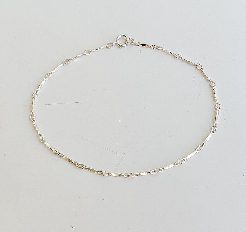 May include: A silver chain anklet with a delicate, linked design.