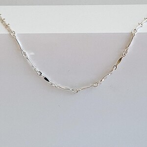 May include: A silver chain necklace with a delicate, elongated link design.