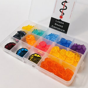 May include: A clear plastic storage box with a blue latch, filled with small, colorful, transparent plastic pieces. The box has a label that reads "Laser Snake Emporium".