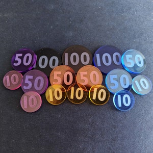 May include: A collection of 14 round plastic chips with various numbers printed on them. The chips are in shades of purple, blue, and orange. The numbers on the chips include 10, 50, and 100.
