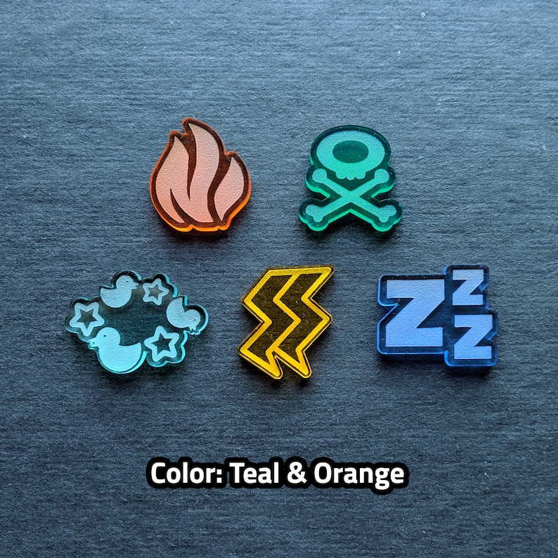 Puede incluir: Cinco fichas de acr&iacute;lico de color turquesa y naranja con diferentes s&iacute;mbolos. Los s&iacute;mbolos son una llama, una calavera y huesos cruzados, un rayo, una nube con p&aacute;jaros y estrellas, y las letras ZZZ.