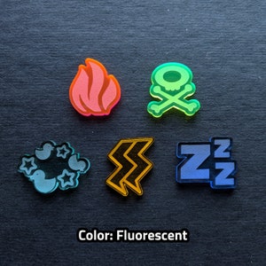 Puede incluir: Cinco fichas acr&iacute;licas fluorescentes diferentes con varios dise&ntilde;os. Las fichas son una calavera y huesos cruzados, una llama, un rayo, una nube con estrellas y una letra Z con una peque&ntilde;a Z encima.