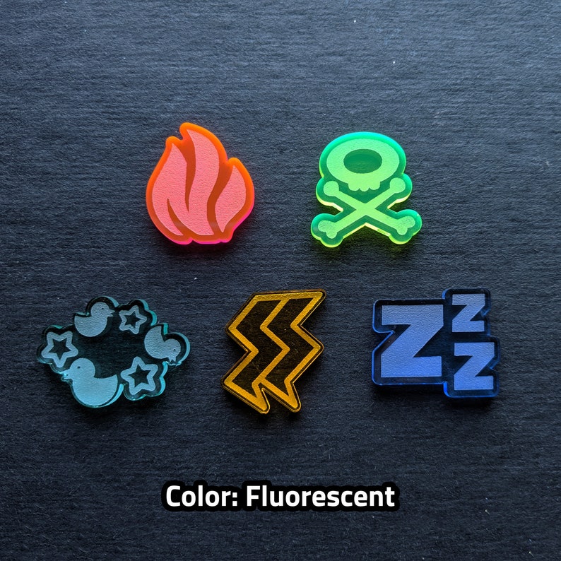 Puede incluir: Cinco fichas acr&iacute;licas fluorescentes diferentes con varios dise&ntilde;os. Las fichas son una calavera y huesos cruzados, una llama, un rayo, una nube con estrellas y una letra Z con una peque&ntilde;a Z encima.