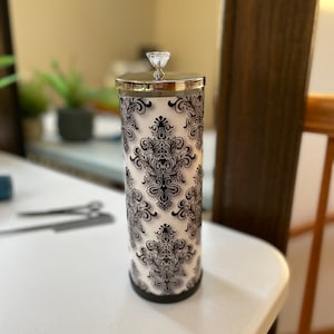 May include: A black and white patterned tumbler with a silver lid and a clear crystal knob. The tumbler has a damask design.