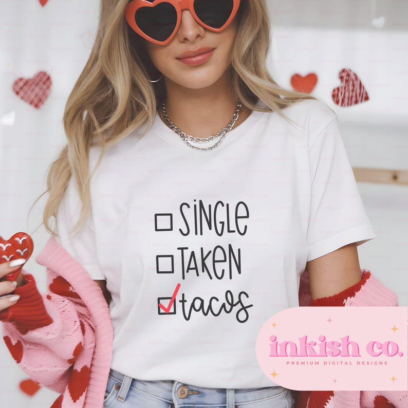 May include: White t-shirt with a black and white graphic that says "Single, Taken, Tacos" with a checkmark next to the word "Tacos".
