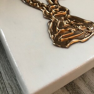 May include: A white canvas with a gold rabbit silhouette. The rabbit is made of raised, textured paint.