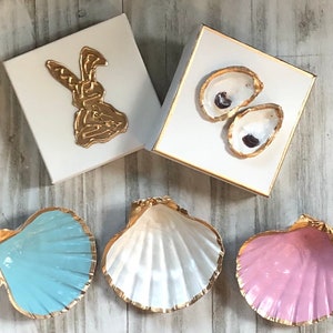 May include: Three decorative seashells with gold trim. The shells are painted in light blue, white, and pink.