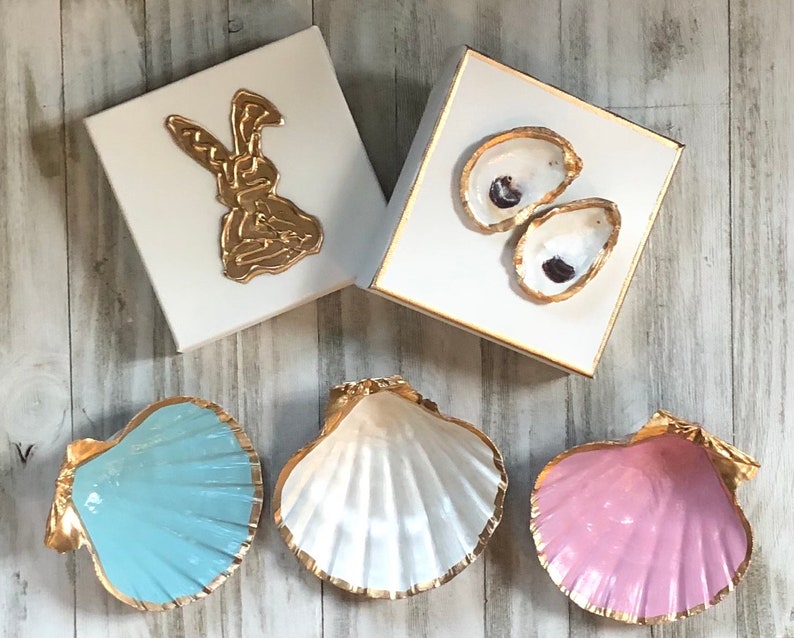 May include: Three decorative seashells with gold trim. The shells are painted in light blue, white, and pink.