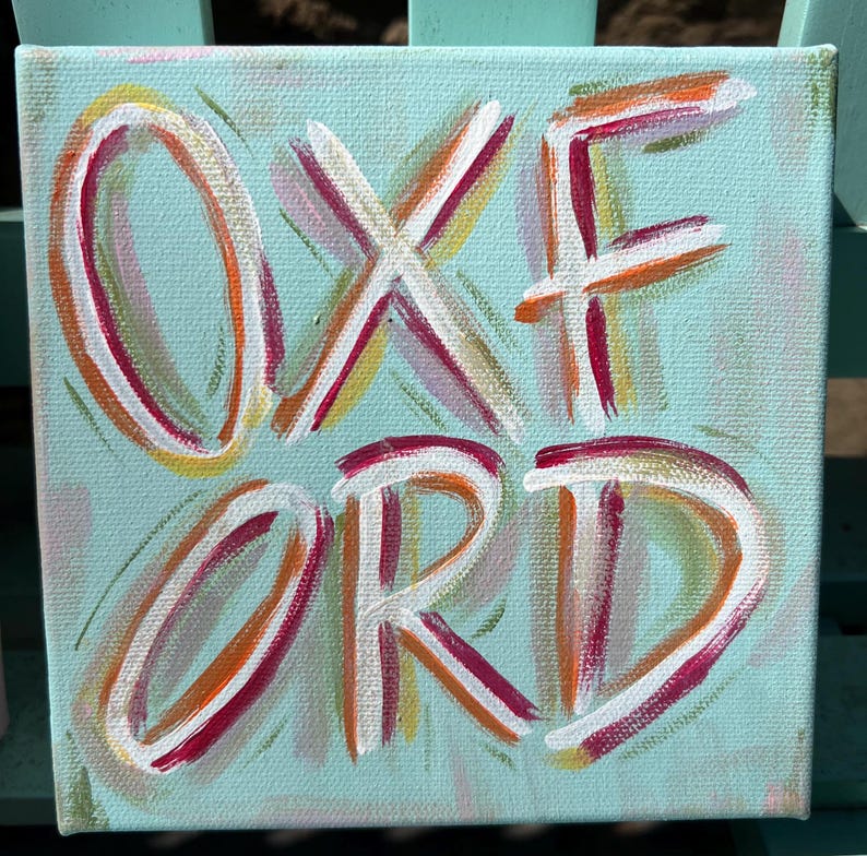 Peut inclure: Une peinture sur toile carr&eacute;e pr&eacute;sentant le mot OXFORD peint en blanc avec des contours superpos&eacute;s orange, rose et jaune. Le fond est d'une couleur vert menthe clair avec des coups de pinceau subtils et doux sur toute la surface.