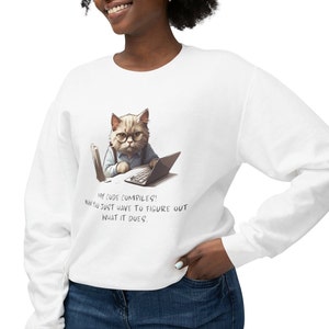 May include: White sweatshirt featuring a graphic of a cat wearing glasses and sitting at a laptop. The text on the sweatshirt reads "My code compiles! Now you just have to figure out what it does."