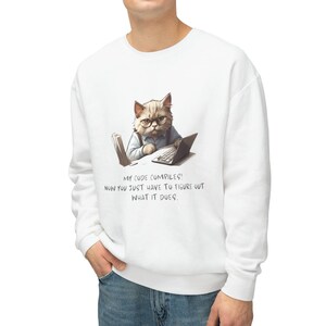 May include: White sweatshirt featuring a cartoon cat wearing glasses and using a laptop. The text on the sweatshirt reads "MY CODE COMPILES! NOW YOU JUST HAVE TO FIGURE OUT WHAT IT DOES."