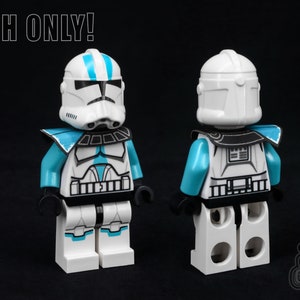 Pode incluir: Uma minifigura LEGO branca de um soldado clone com um capacete azul e branco e uma armadura azul e branca. A minifigura está usando um cinto preto e tem uma peça de peito preta e branca. A minifigura está em pé sobre um fundo preto. "CLOTH ONLY!" está escrito em branco no topo da imagem.