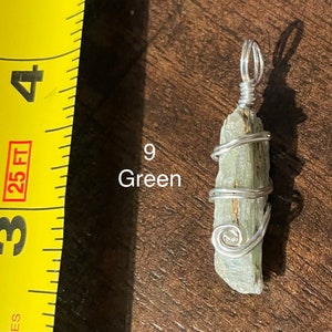 Peut inclure: Un pendentif en cristal vert envelopp&eacute; de fil d'argent. Le pendentif mesure environ 5 cm de long et est suspendu &agrave; une cha&icirc;ne en argent.