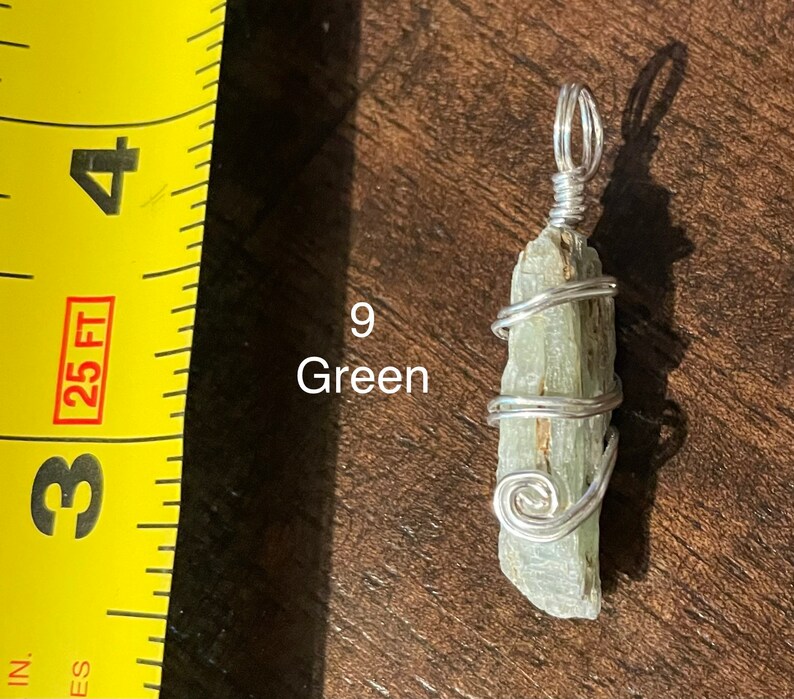 Peut inclure: Un pendentif en cristal vert envelopp&eacute; de fil d'argent. Le pendentif mesure environ 5 cm de long et est suspendu &agrave; une cha&icirc;ne en argent.