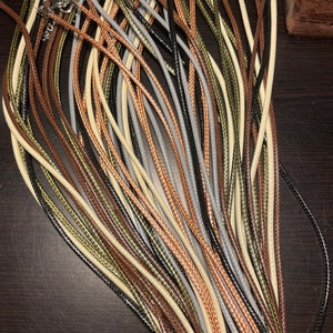 Peut inclure: Un ensemble de cordons de diff&eacute;rentes couleurs, dont le noir, le marron, le beige et le vert, dispos&eacute;s en &eacute;ventail. Les cordons sont en mat&eacute;riau tress&eacute; et ont une texture lisse.