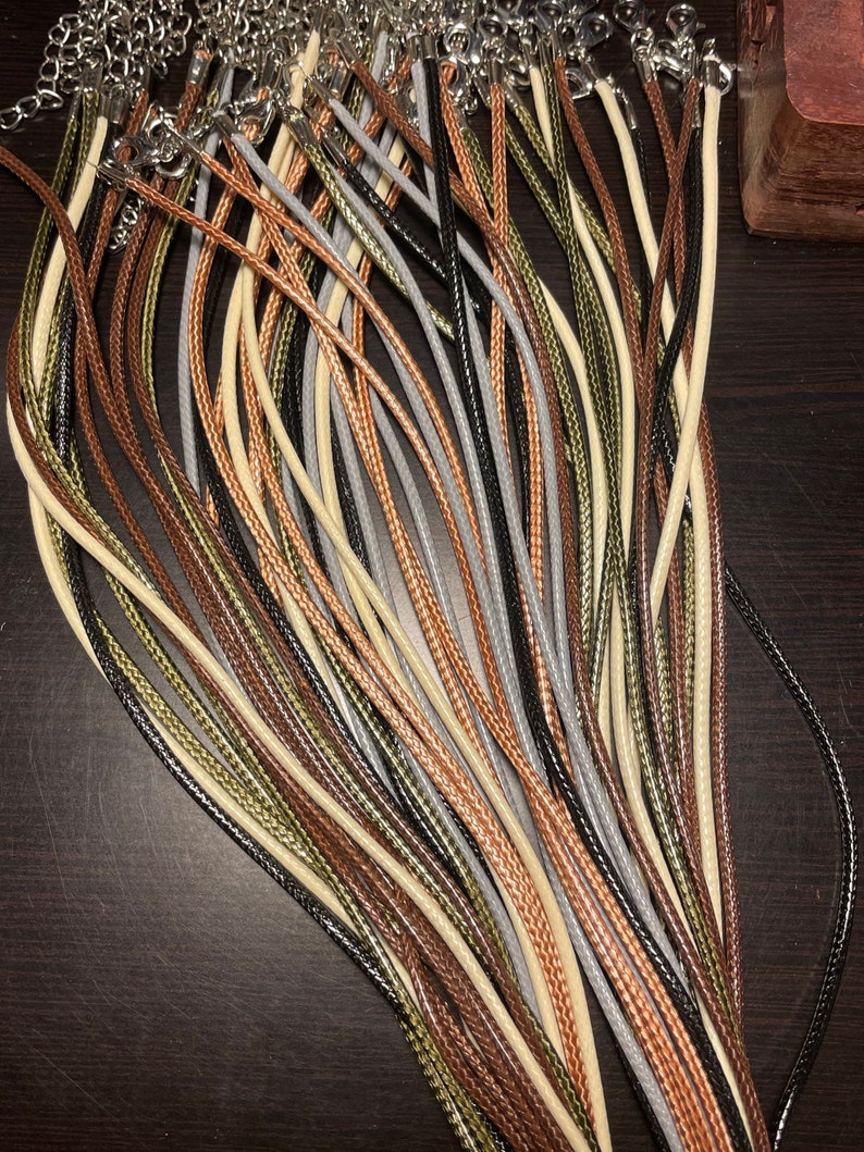 Peut inclure: Un ensemble de cordons de diff&eacute;rentes couleurs, dont le noir, le marron, le beige et le vert, dispos&eacute;s en &eacute;ventail. Les cordons sont en mat&eacute;riau tress&eacute; et ont une texture lisse.