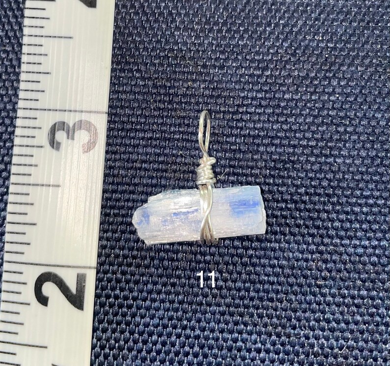 Peut inclure: Un pendentif en fil d'argent enroul&eacute; autour d'un cristal de s&eacute;l&eacute;nite bleu clair. Le cristal mesure environ 2,5 cm de long.