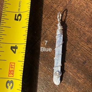 Peut inclure: Un pendentif en cristal bleu envelopp&eacute; de fil d'argent. Le pendentif mesure environ 5 cm de long et a une petite perle d'argent au bas.