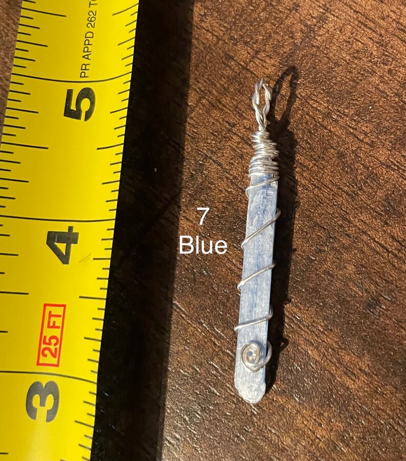 Peut inclure: Un pendentif en cristal bleu envelopp&eacute; de fil d'argent. Le pendentif mesure environ 5 cm de long et a une petite perle d'argent au bas.