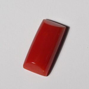 May include: A rectangular, red coral cabochon with rounded edges.