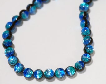 May include: A necklace made of blue and black glass beads. The beads have a speckled, iridescent finish.