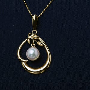 May include: A gold pendant necklace with a teardrop design and a pearl. The pendant has a floral accent and hangs from a fine chain. The pearl is a soft, off-white colour. The necklace is a piece of jewellery.
