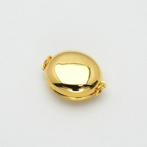 May include: A gold-toned oval-shaped clasp with a smooth, shiny finish. The clasp has two small loops on either side for attaching jewellery.