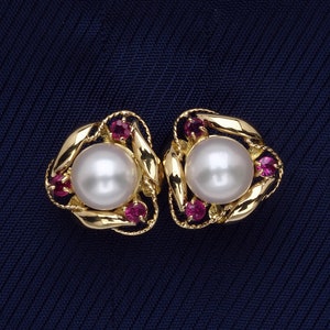 May include: A pair of gold earrings with a pearl and pink gemstones. The earrings are in the shape of a triangle.