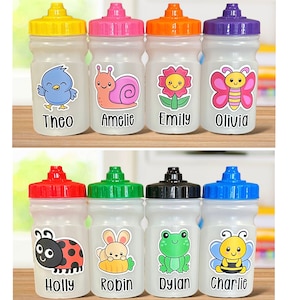 May include: Eight clear plastic water bottles with colourful lids and personalised labels featuring cartoon animal designs and names. The names on the bottles are Theo, Amelie, Emily, Olivia, Holly, Robin, Dylan, and Charlie.