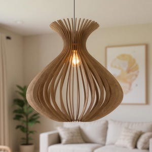 Könnte beinhalten: Eine Holz-Pendelleuchte mit einem einzigartigen, offenen Design hängt von der Decke. Das Licht hat eine Glühbirne im Inneren, und die Leuchte besteht aus vertikalen Holzlatten. Die Szene ist ein Wohnzimmer.
