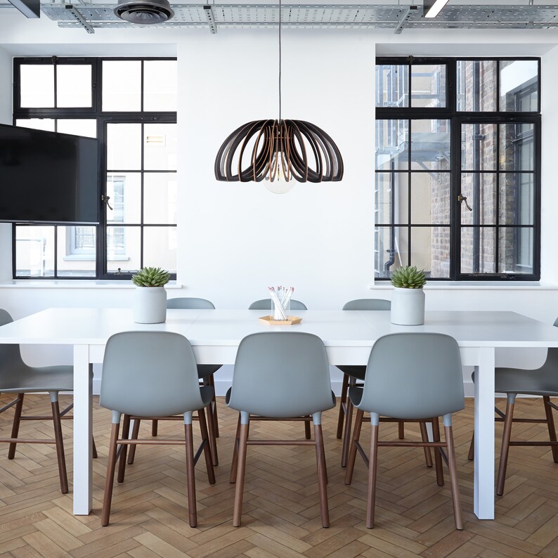 May include: A white table with six gray chairs and a wooden slat pendant light hanging above it. The table is set in a modern office space with large windows and a wood floor.